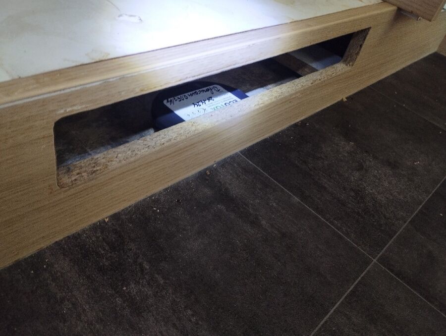 Hinter einer offenen Holzverkleidung in Steinhausen (6312, Kanton Zug), ist eine schwarze Köderbox zur Insektenbekaempfung platziert.