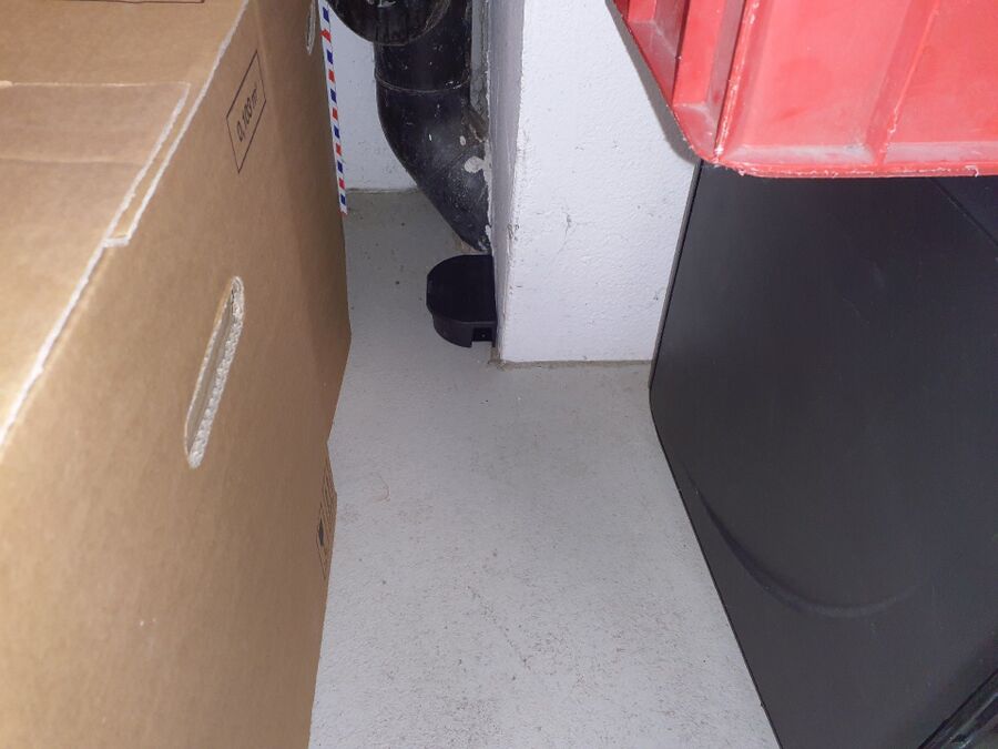 In einem Kellerraum in Unterägeri (6314, Kanton Zug), steht eine schwarze Köderbox neben einem Rohr an der Wand.