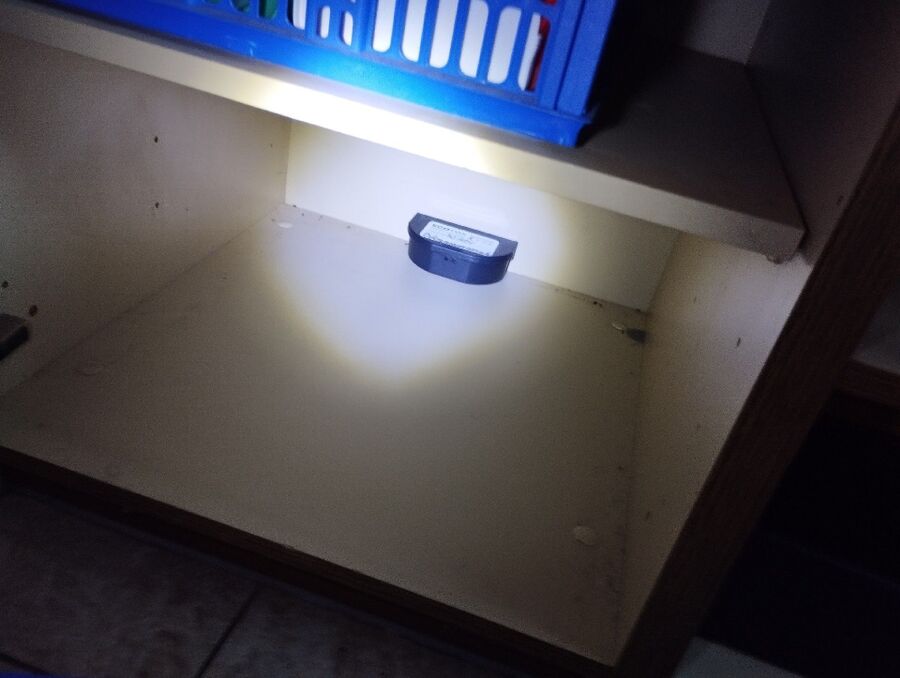 In einem Schrank in Zug (6300, Kanton Zug), steht eine schwarze Köderbox zur Insektenbekaempfung auf der unteren Ablage.