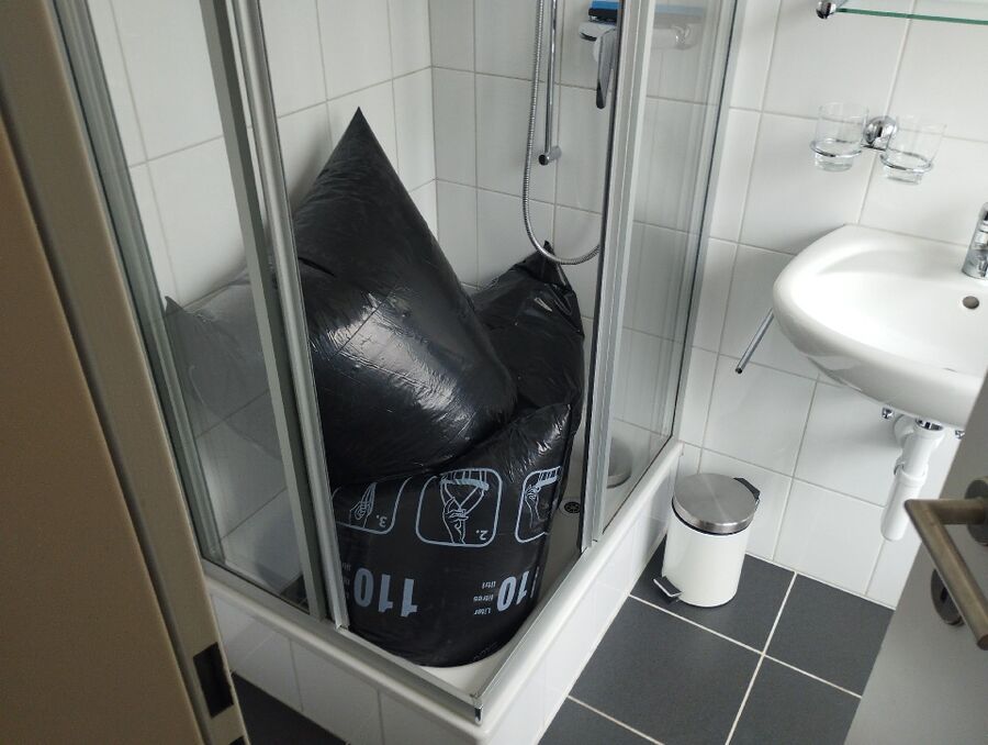 In einer Dusche in Oberägeri (6315, Kanton Zug), stehen grosse schwarze Saecke, wodurch ein moeglicher Befall zusaetzlich verdeckt sein koennte.